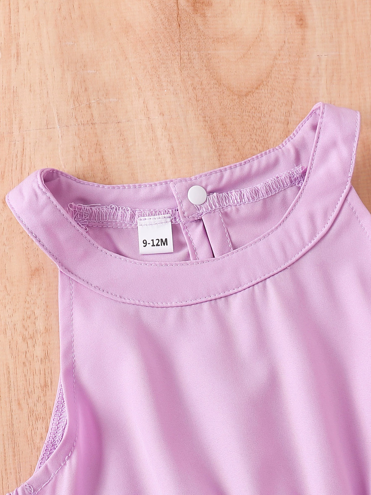 Lilac toddler dress with a round neckline and button closure at the back.