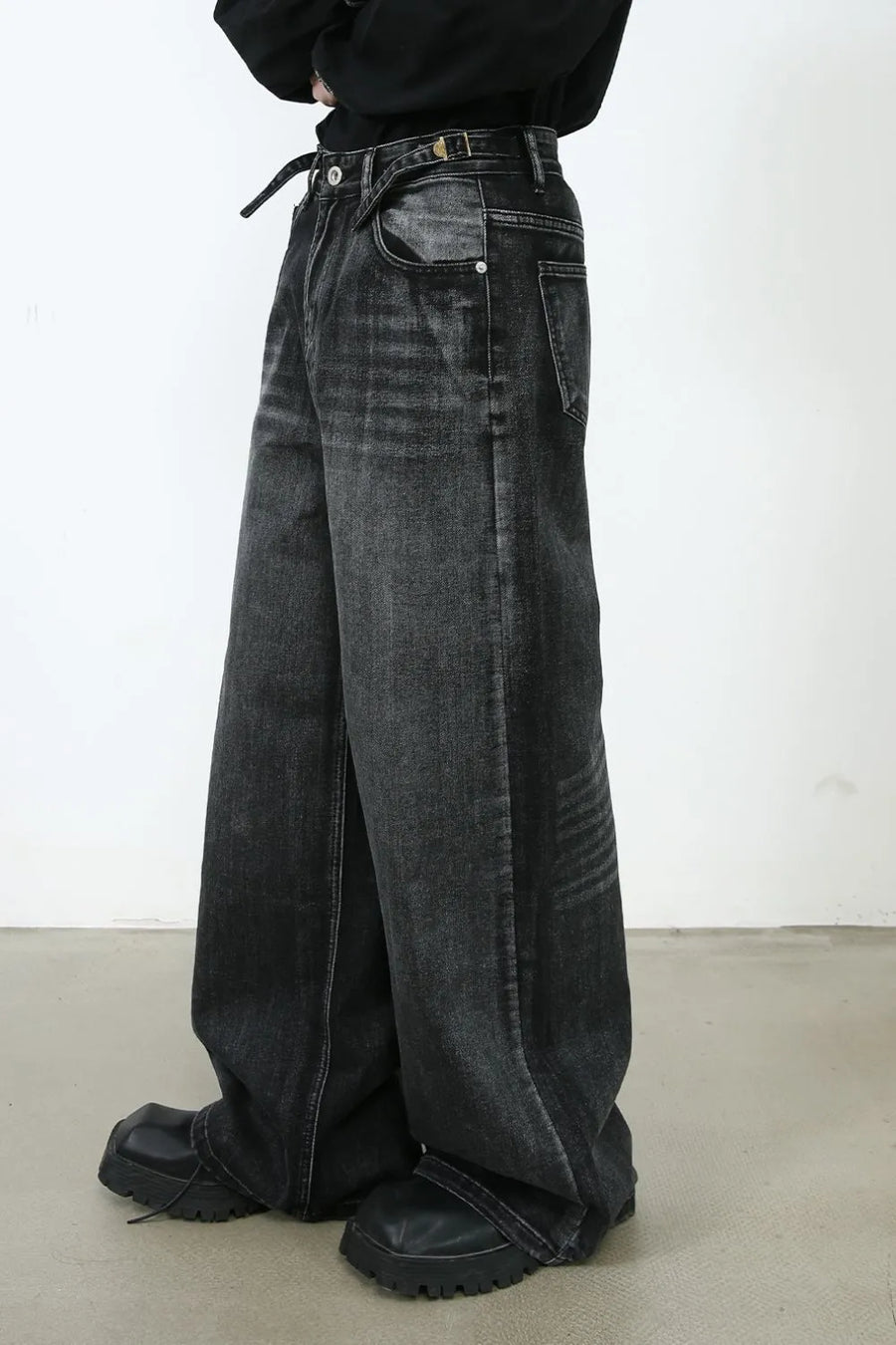 Dark sculpted flare denim trousers with a wide leg and belt detail.