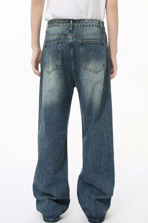 Pleated baggy denim jeans in medium wash with a relaxed fit and distressed details.