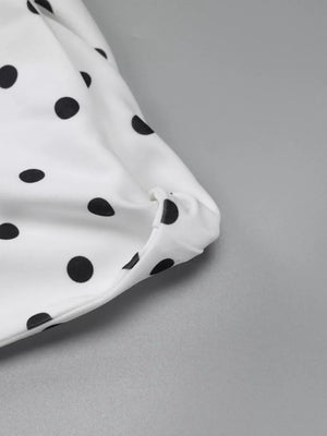 White polka dot mini dress with asymmetrical hem and bow detail.