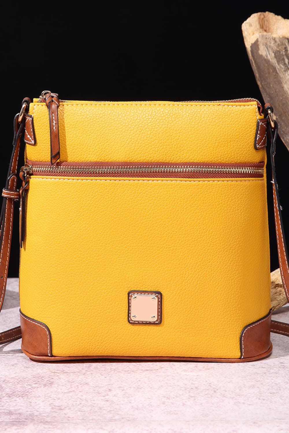 Yellow leather crossbody bag with brown trim and two zippered compartments.