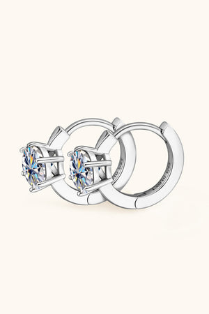 Silver moissanite solitaire huggie hoop earrings with prong-set round cut stones.