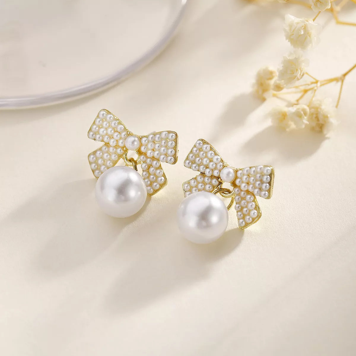 Gold bowknot pearl drop earrings with 18K gold plating.