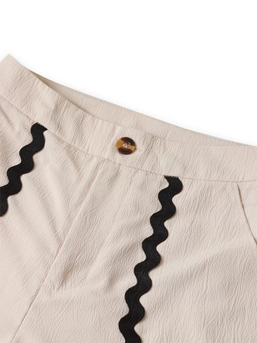 Cream pajama shorts with black scalloped trim and button closure.