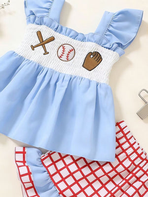 Baby girl's blue cotton smocked top with baseball embroidery and red checkered shorts.
