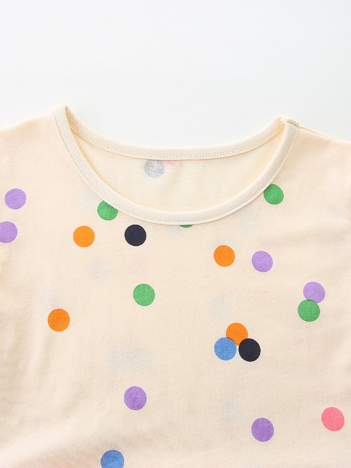 Cream cotton toddler dress with colorful polka dots and a round neckline.