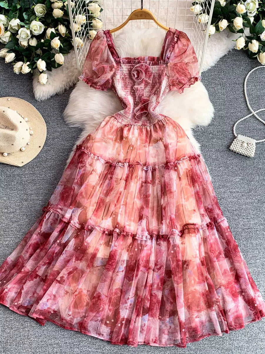 Floral tiered midi dress with smocked bodice, puff sleeves, and square neckline in a watercolor pink and red print.