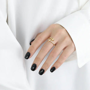 Gold crossed paths open ring with pave detail on a hand with black nails