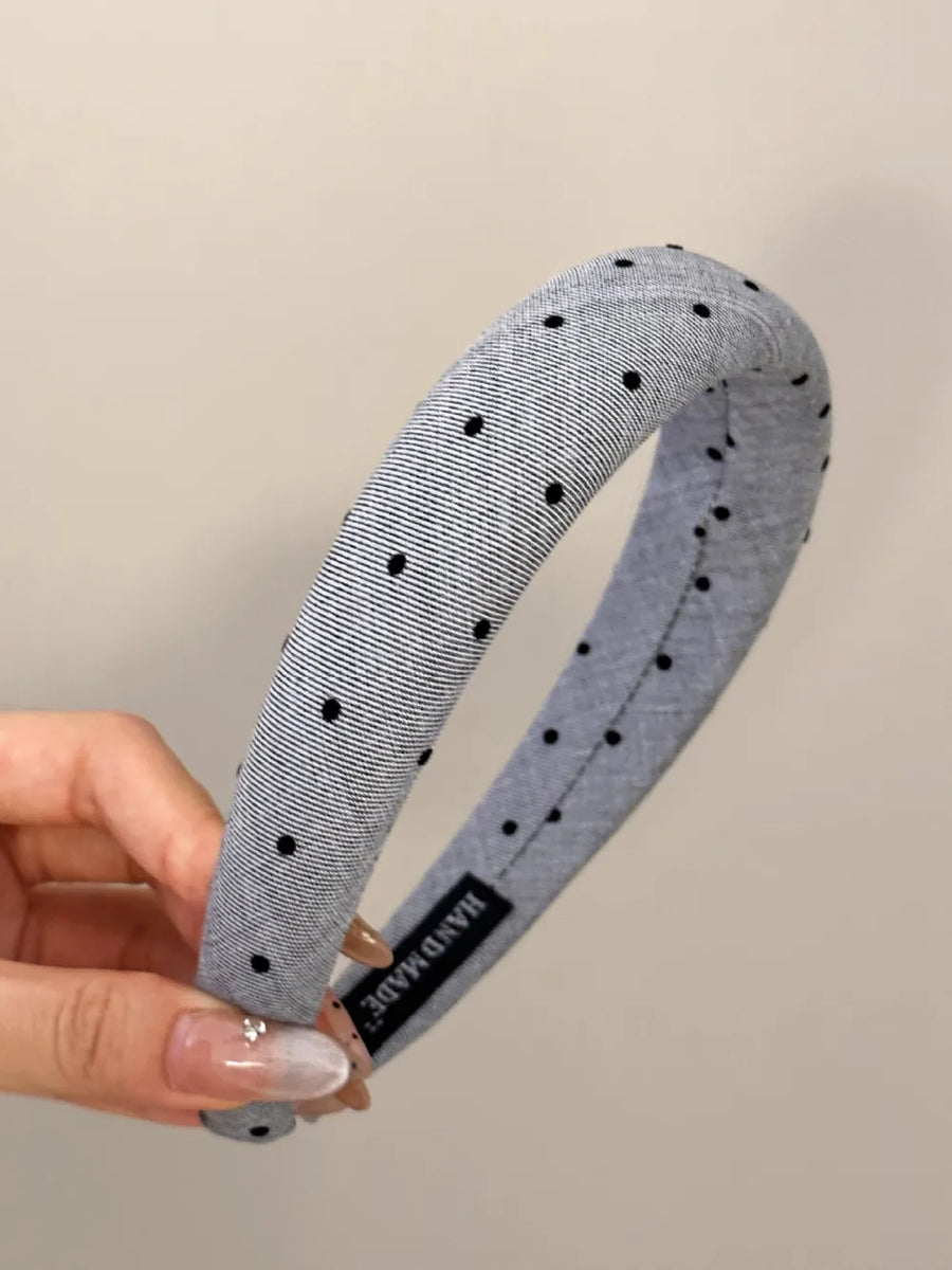Padded headband in dark gray with black polka dots and a handmade label.