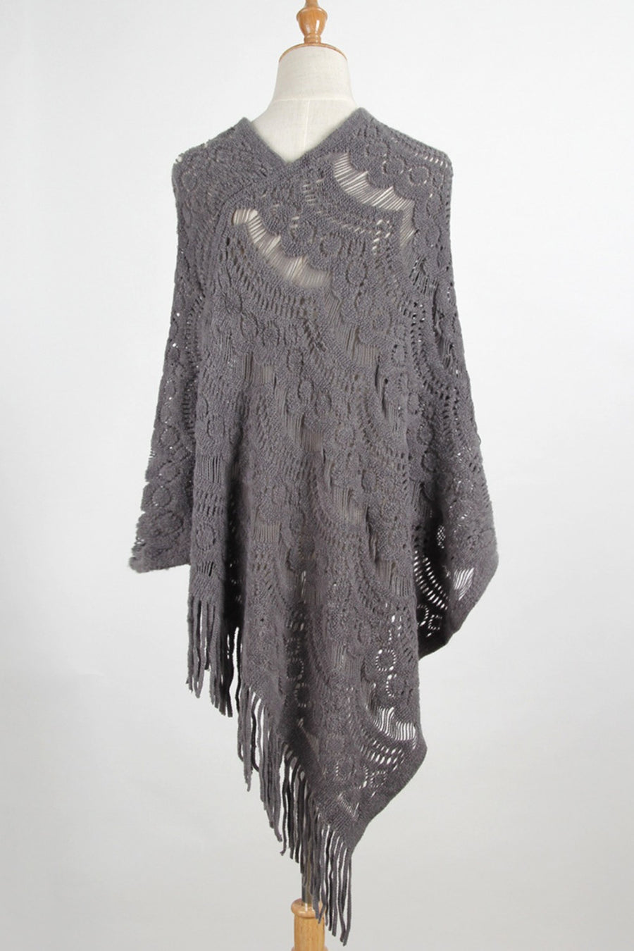 Dark gray crochet poncho with intricate openwork pattern and fringe detail.