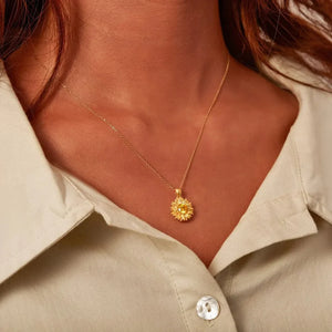 Gold sunflower pendant necklace with yellow gemstone detail on a delicate chain.