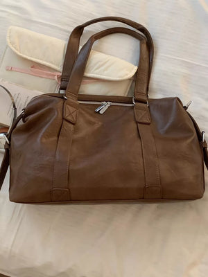Brown pu leather shoulder bag with double handles and a charm detail.