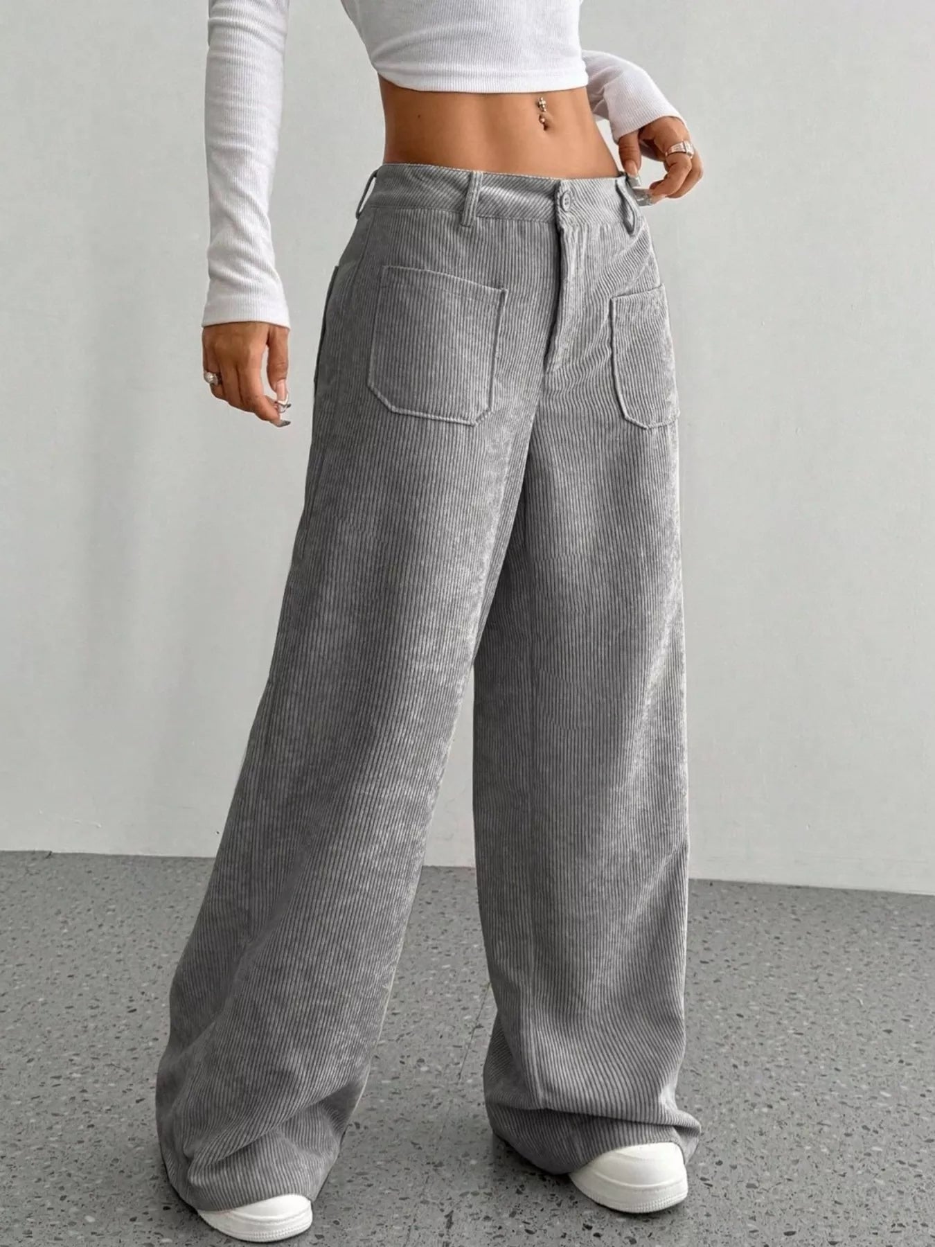 Grey corduroy wide-leg trousers with large front pockets and a relaxed fit.