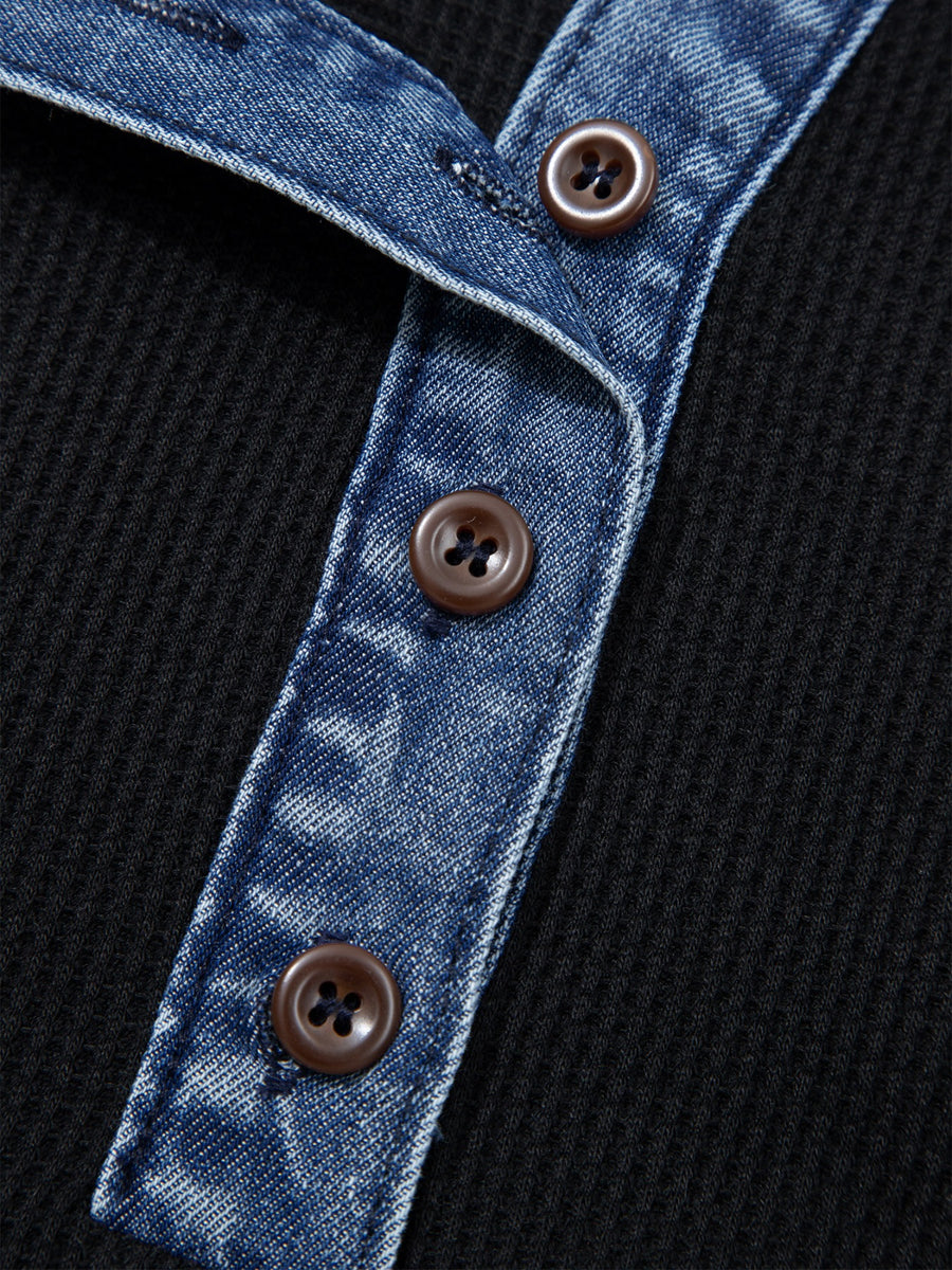 Black textured knit polo top with button-down placket and denim trim detail.