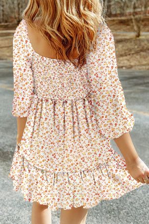 Floral smocked mini dress with tiered ruffles and 3/4 sleeves in a beige floral print.