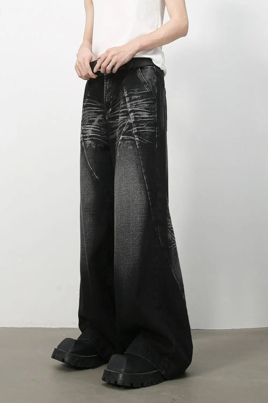Dark wash wide leg jeans with sculpted details and a faded cat's whisker pattern.
