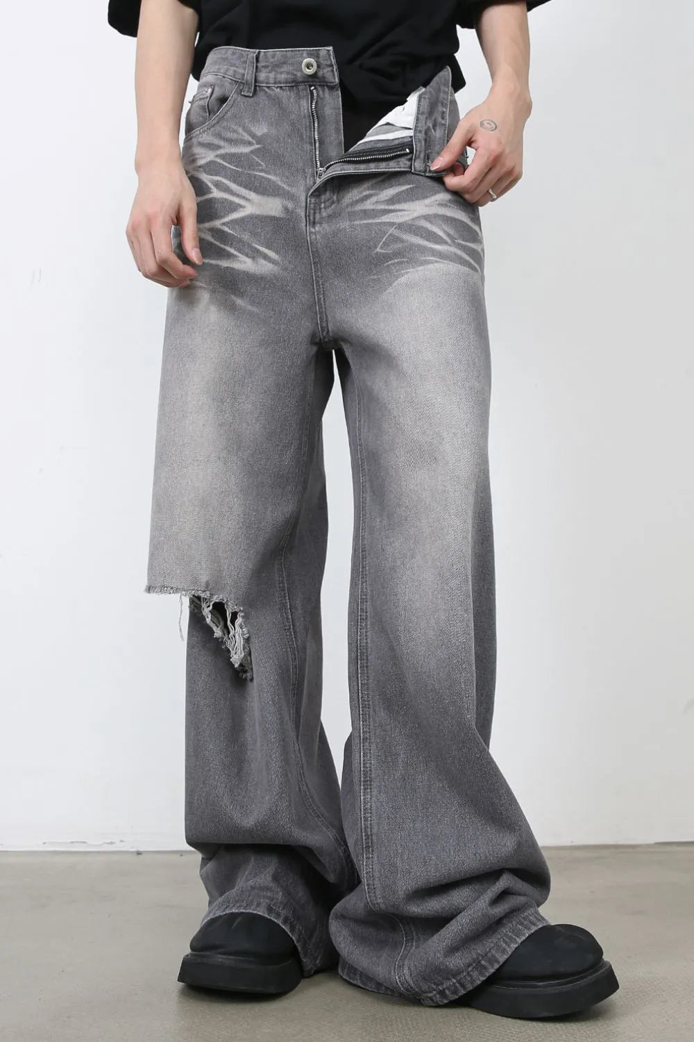 Distressed dark gray wide-leg denim jeans with a ripped thigh detail and faded wash.