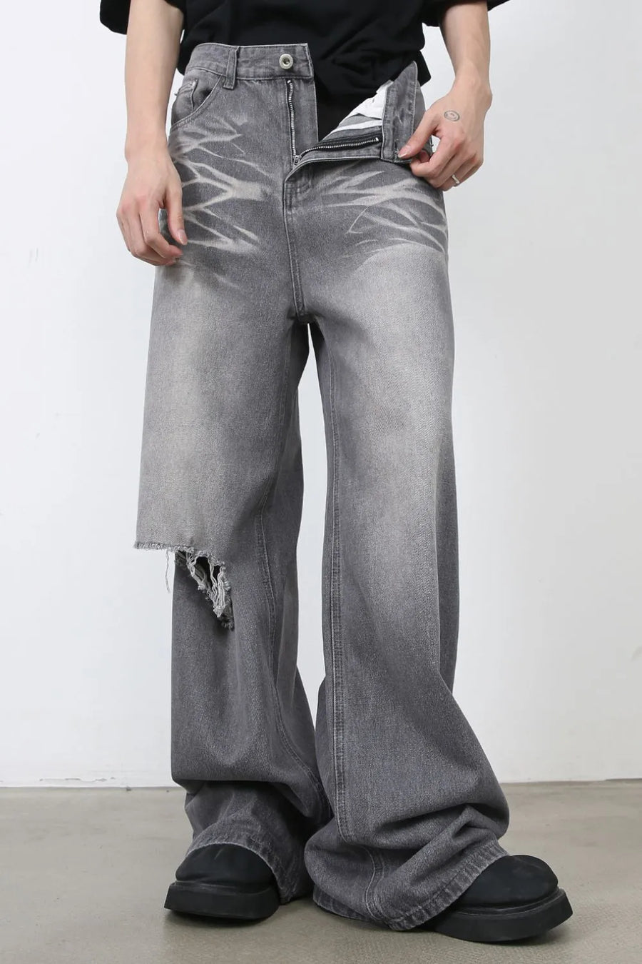 Distressed dark gray wide-leg denim jeans with a ripped thigh detail and faded wash.