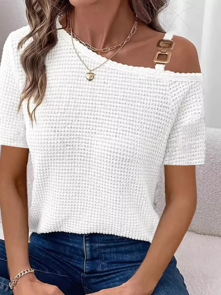 White waffle knit one-shoulder t-shirt with gold buckle detail on strap.