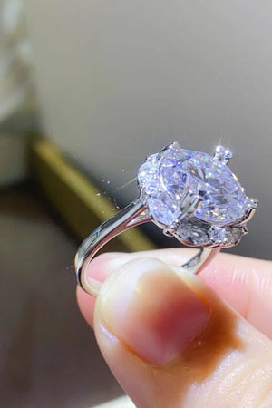 Silver moissanite ring with a large pear-shaped center stone and halo accent stones.