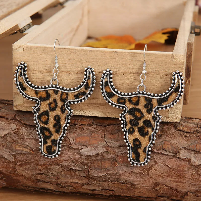 Leopard print bull head drop earrings with silver trim and hooks.