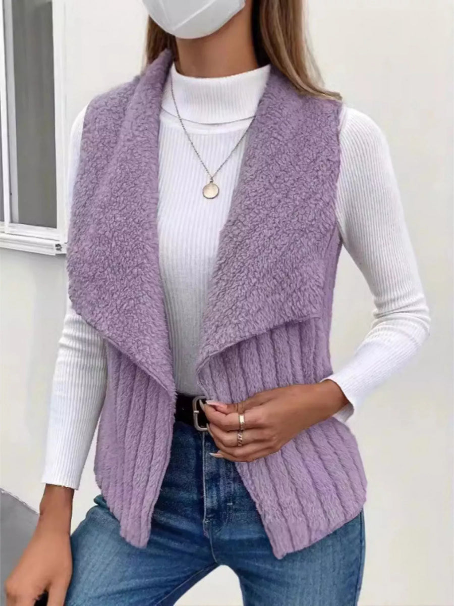 Purple open front fleece vest with shawl collar and ribbed texture, styled with a white turtleneck and jeans.