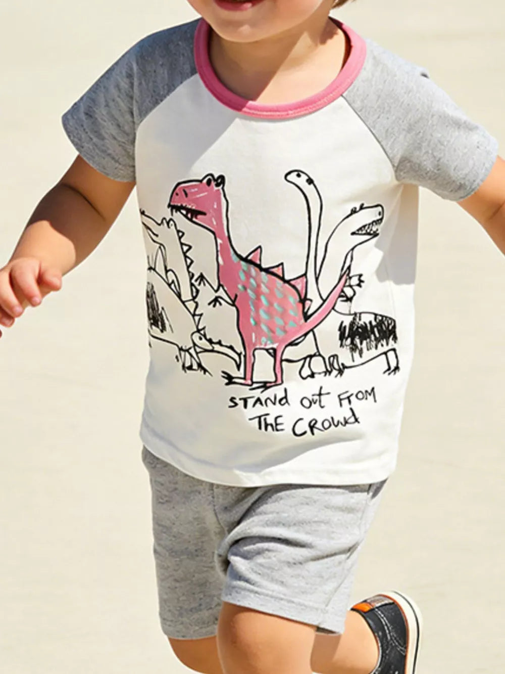 Toddler t-shirt with playful dinosaur print, pink trim, and cotton fabric.