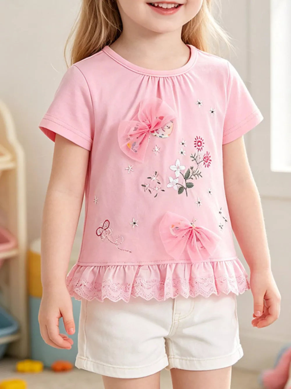 Pink cotton t-shirt with floral embroidery, tulle bows, and lace trim.