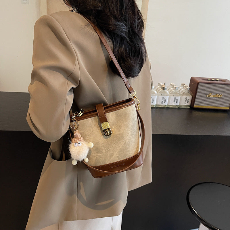 Vintage bucket crossbody bag in tan with brown trim and a cute charm.
