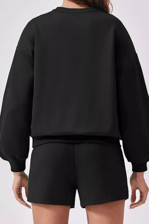 Black sweatshirt with balloon sleeves and ribbed cuffs, paired with matching shorts.