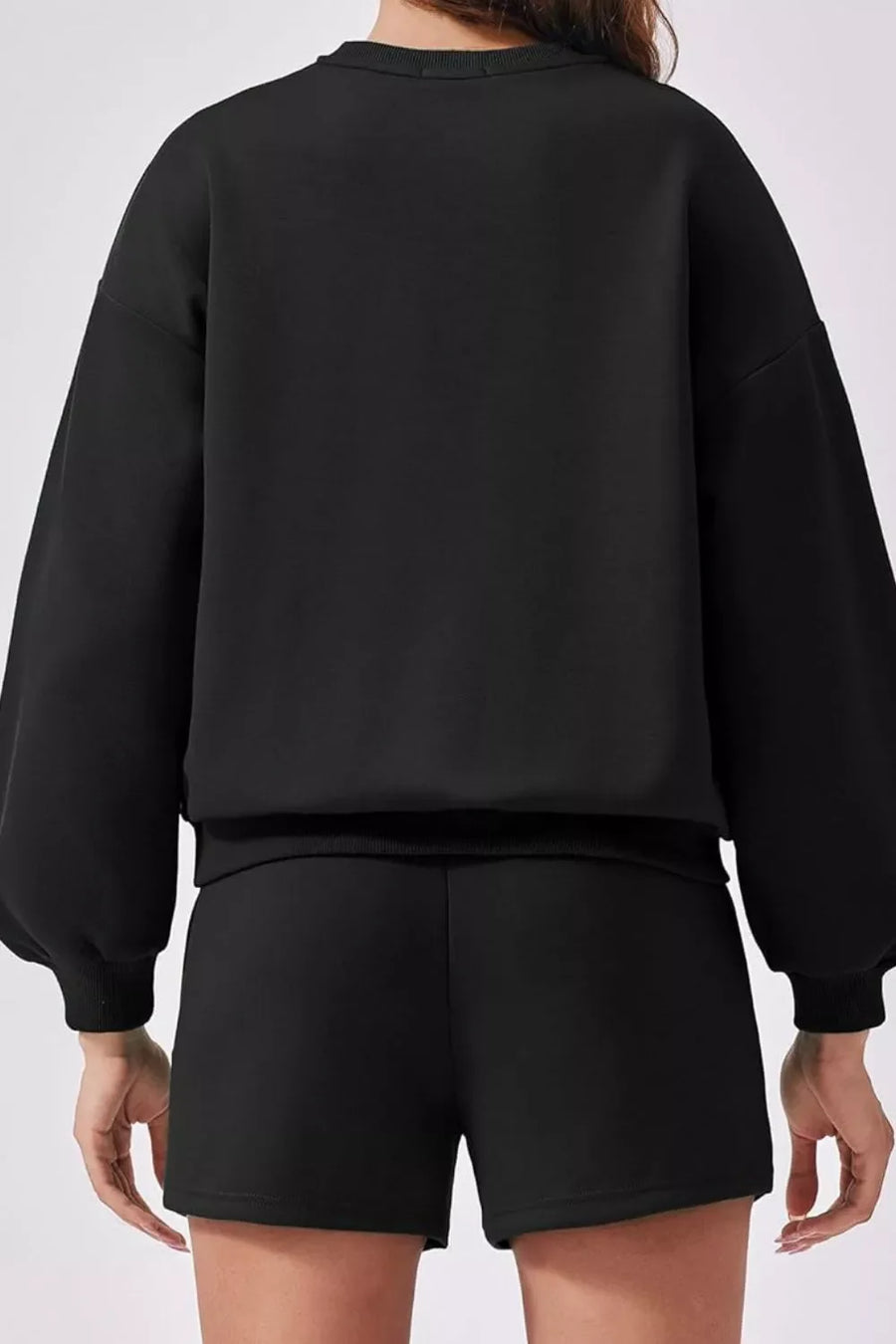 Black sweatshirt with balloon sleeves and ribbed cuffs, paired with matching shorts.