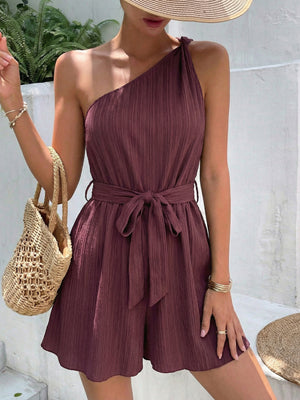 Chic one-shoulder romper in plum with tie waist and textured fabric.