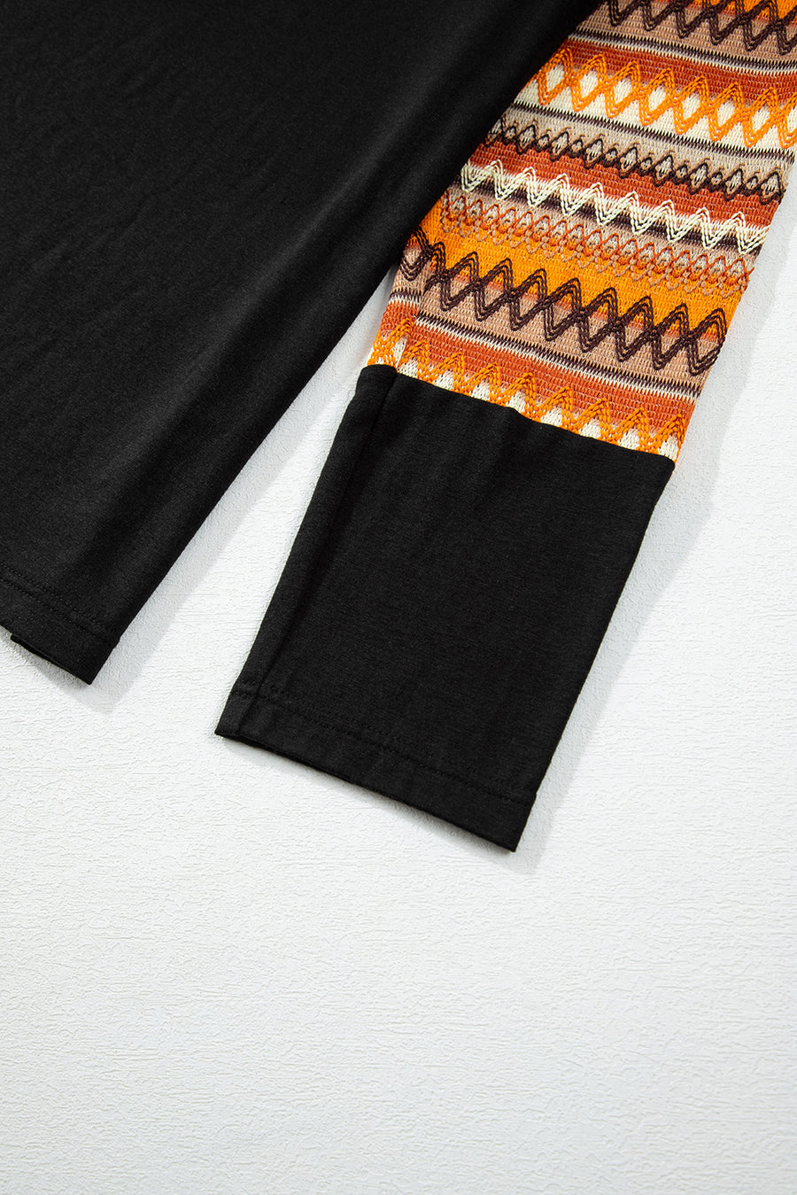 Black raglan tee with Aztec patterned sleeves in tangerine and brown.