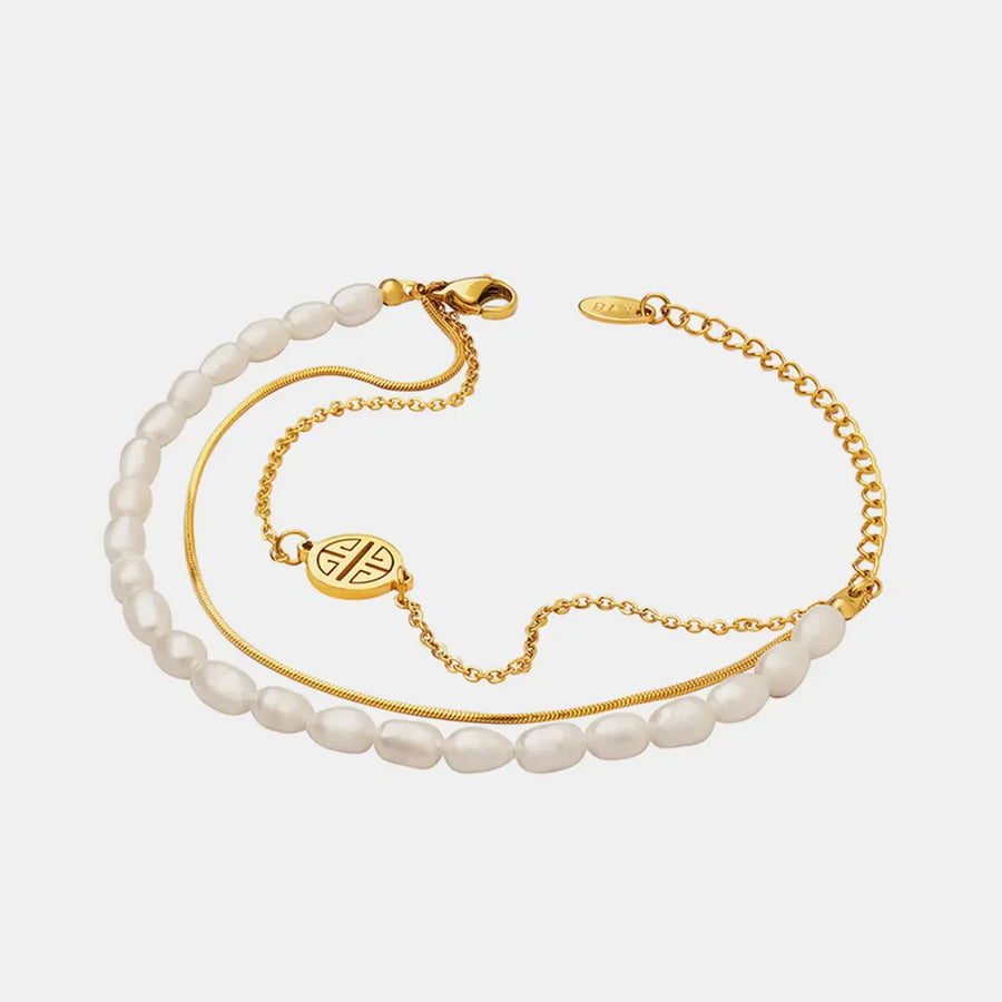 Gold layered bracelet with pearls, chain, and a circular charm.