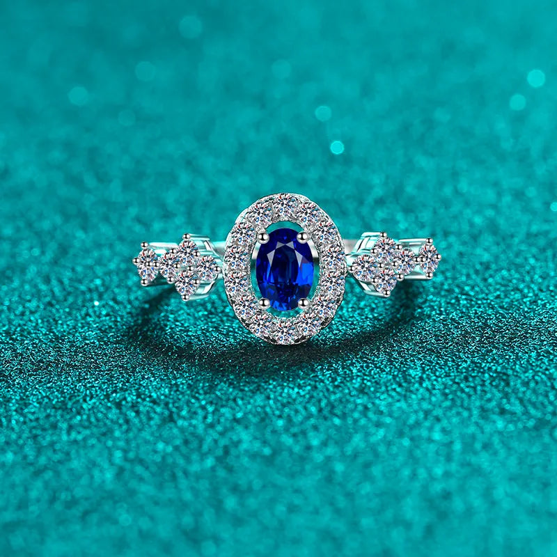 Silver oval sapphire halo ring with diamond cluster accents.