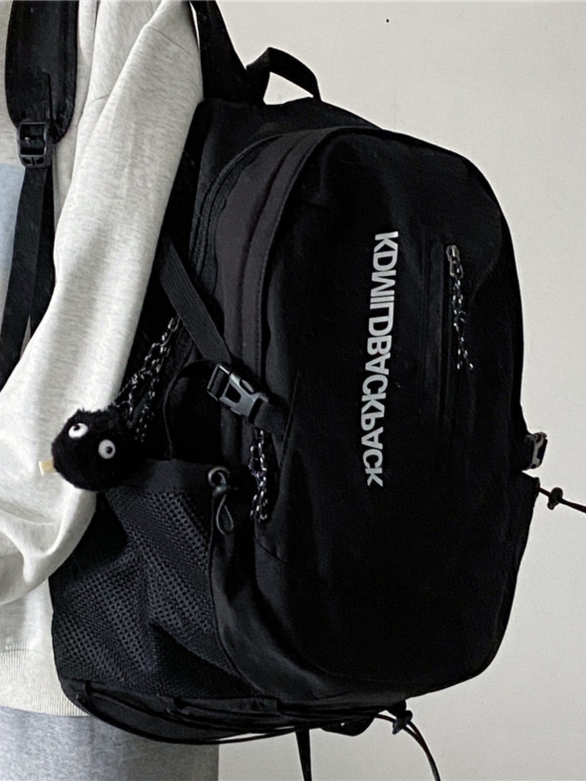 Black nylon casual backpack with zippered pocket and mesh side pocket.