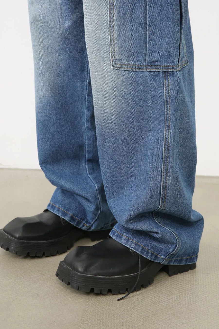 Faded denim cargo pants in medium wash with a relaxed fit and large cargo pocket detail.