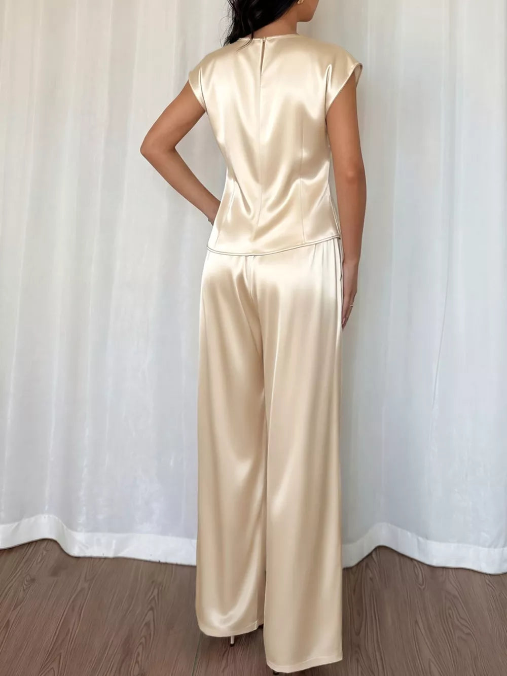 Champagne satin twist-front top with cap sleeves and flowing wide-leg pants.