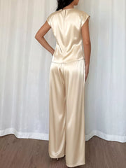 Champagne satin twist-front top with cap sleeves and flowing wide-leg pants.