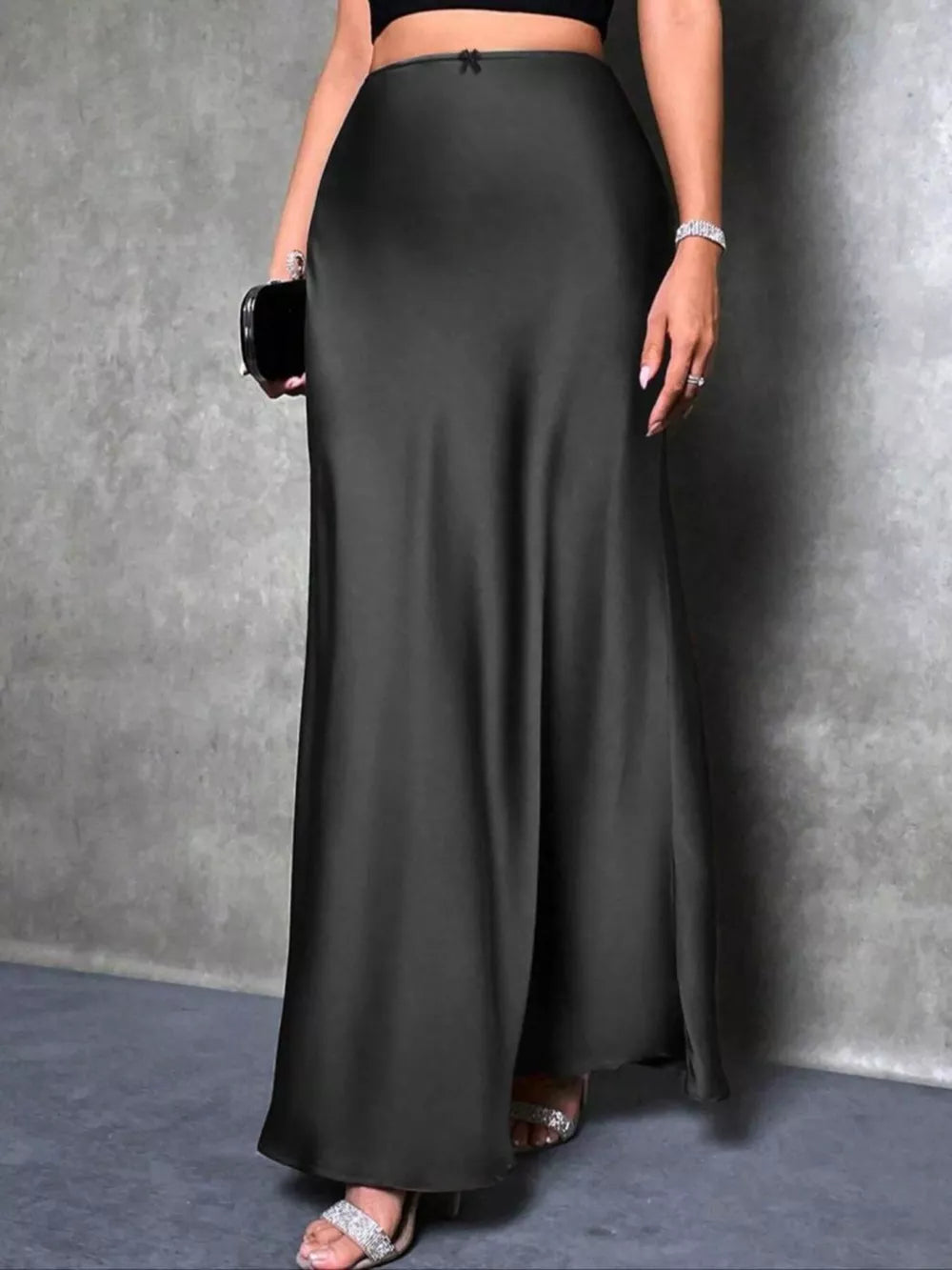 Elegant black satin maxi skirt with high waist and bow detail.