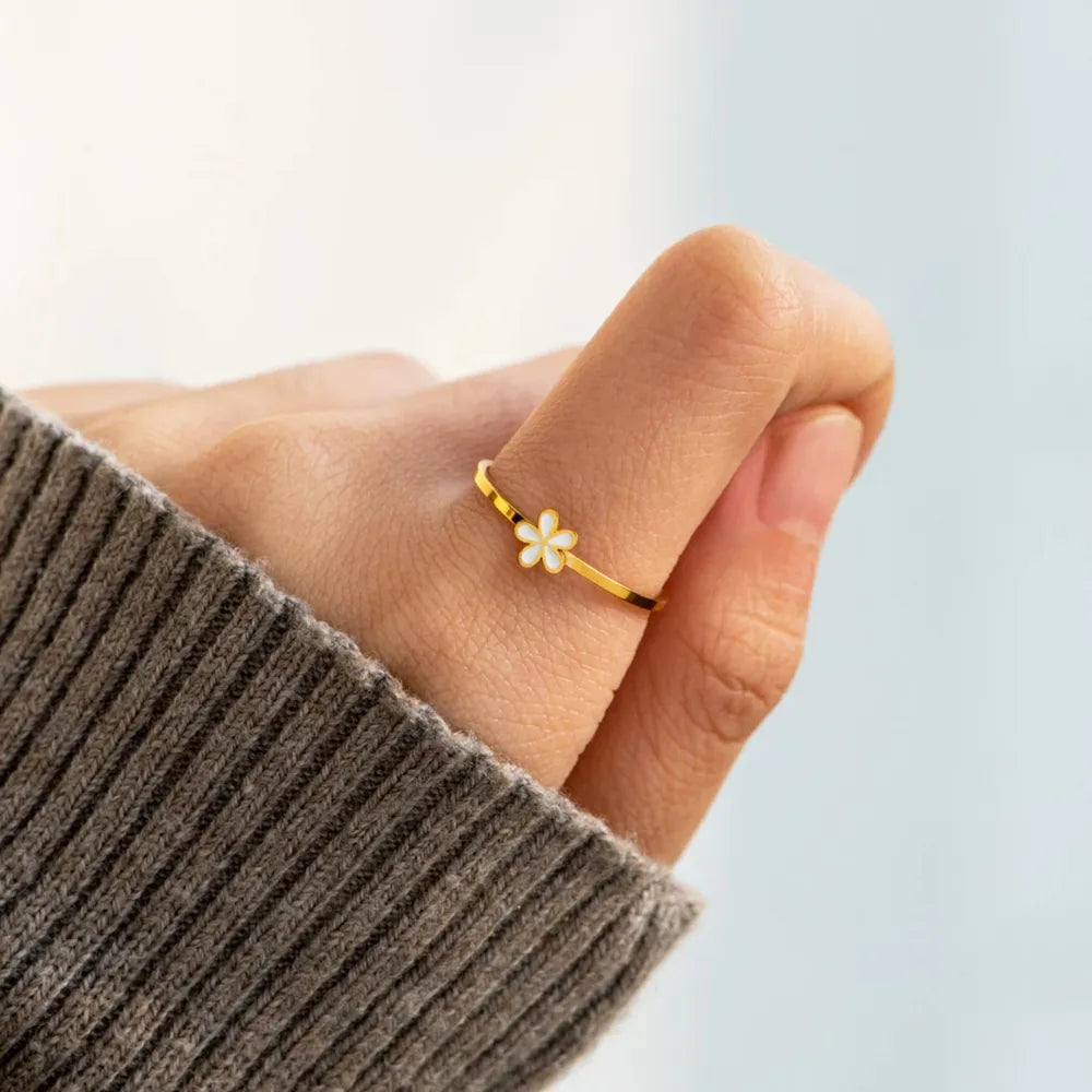 Delicate floral enamel ring with white bloom detail on gold band.