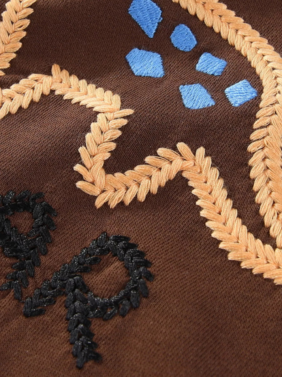 Dark brown sweatshirt with embroidered dinosaur details, wheat-like accents, and blue shapes.