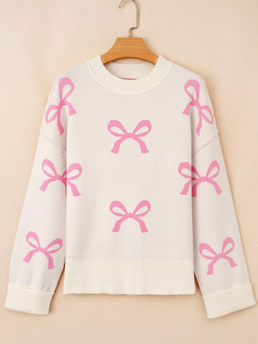 Beige drop shoulder sweater with allover pink bow print, crew neck, and ribbed cuffs and hem.