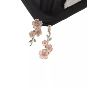 Asymmetrical blush pink floral drop earrings with green leaves.
