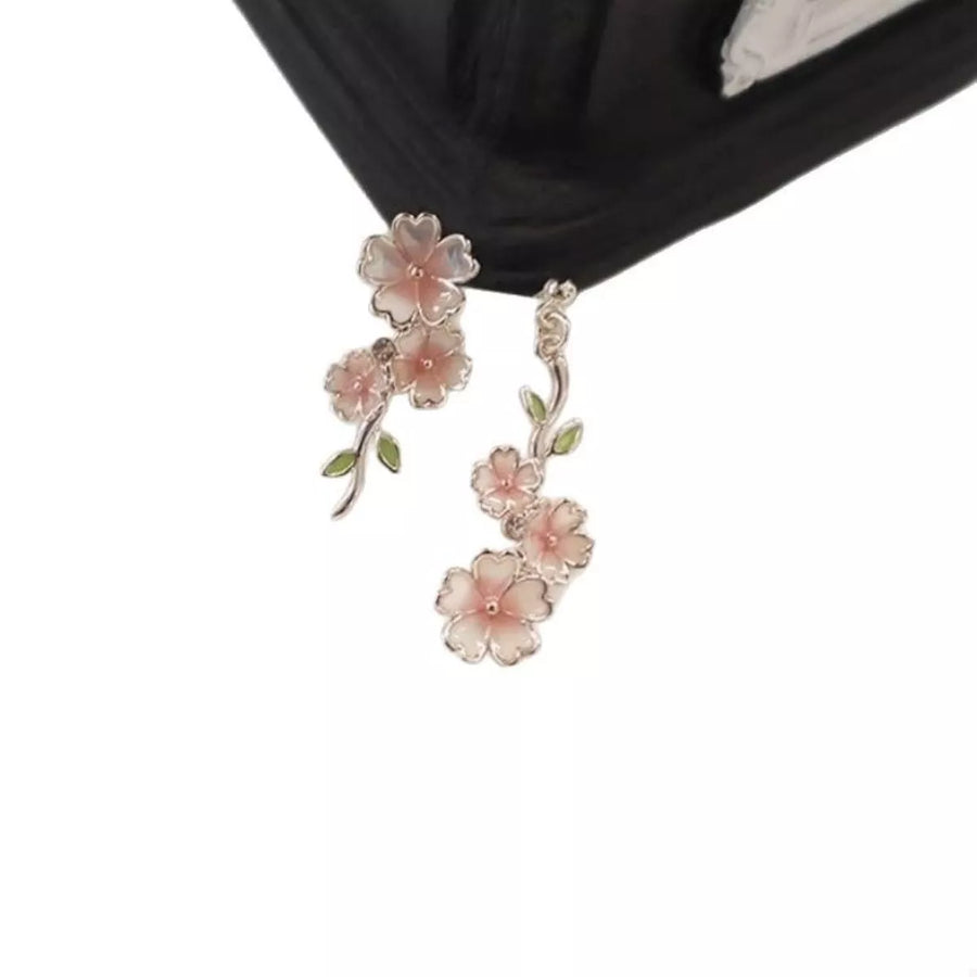 Asymmetrical blush pink floral drop earrings with green leaves.