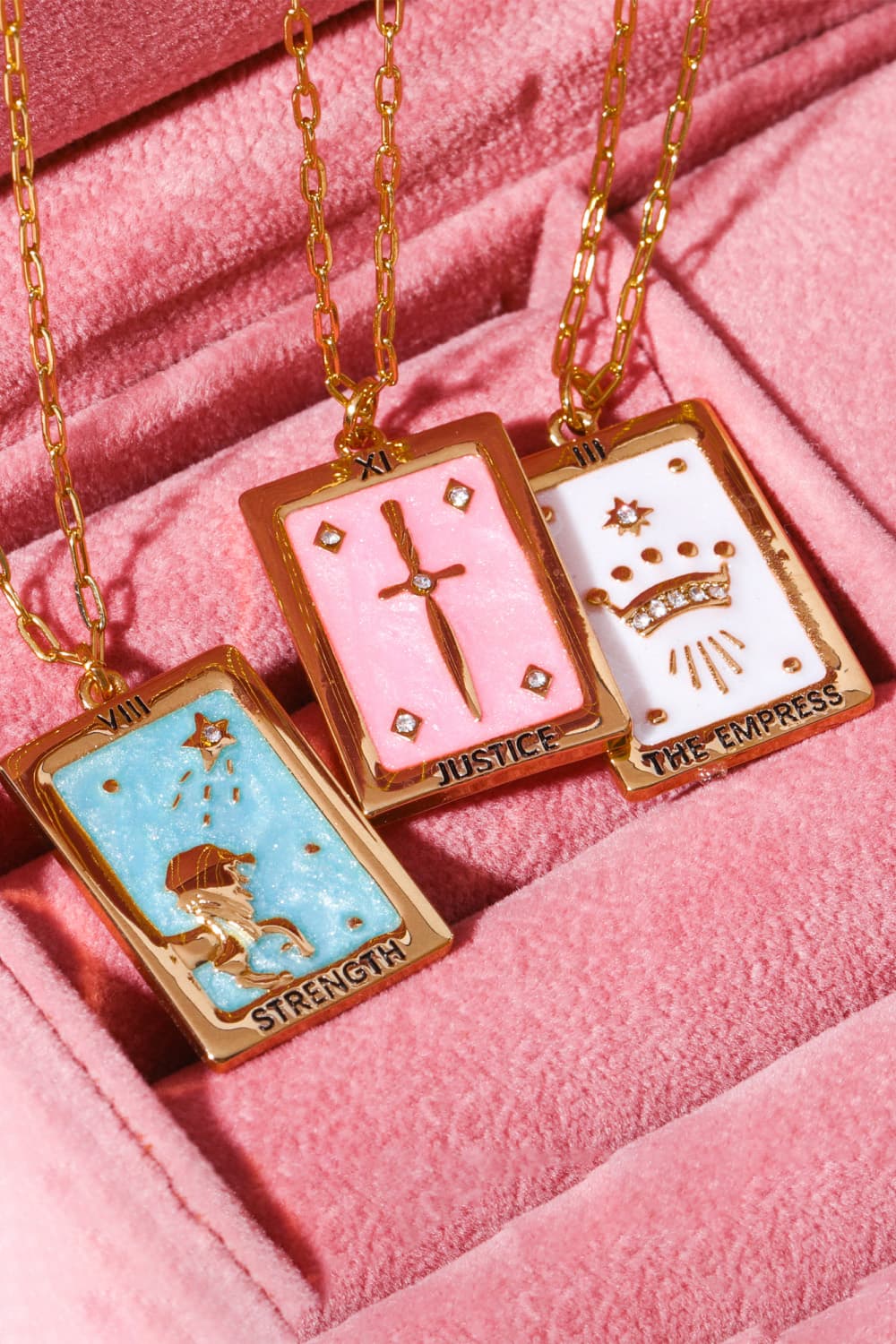 Tarot card pendant necklaces in light blue, blush pink, and white with gold chain and charms.
