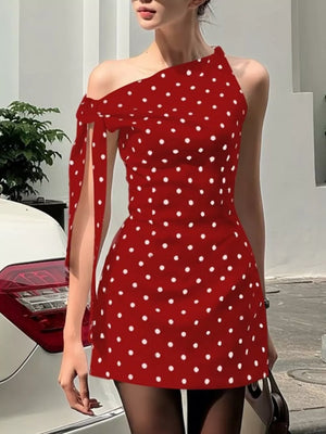 Red polka dot mini dress with asymmetrical neckline and bow detail on shoulder.