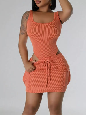 Orange ribbed knit tank top and mini skirt set with drawstring waist and pocket details.
