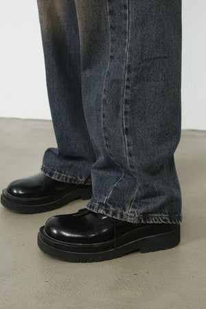 Baggy dark wash denim jeans with a faded effect, styled with black platform shoes.