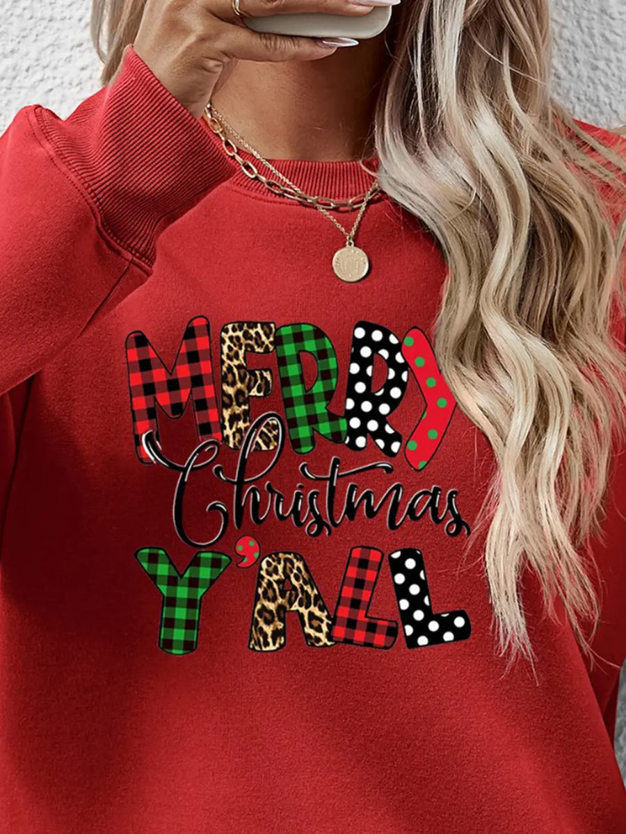 Red crewneck sweatshirt with "Merry Christmas Y'all" graphic in mixed prints of plaid, leopard, and polka dots.